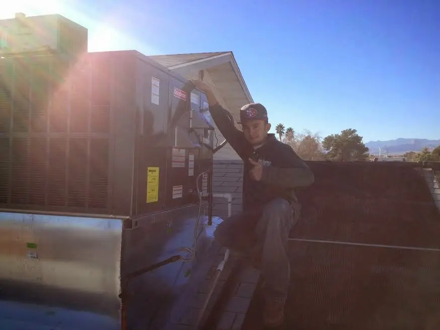HVAC technician performing Air Duct Repair on a rooftop unit in Kerrville